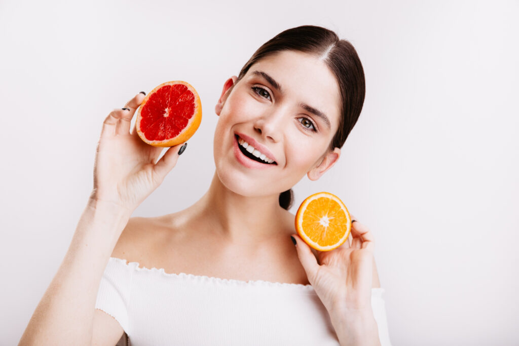 adorable girl with friendly smile white wall woman without makeup holds slices juicy orange grapefruit