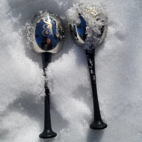 Two spoons in the snow with a picture of a man on them.