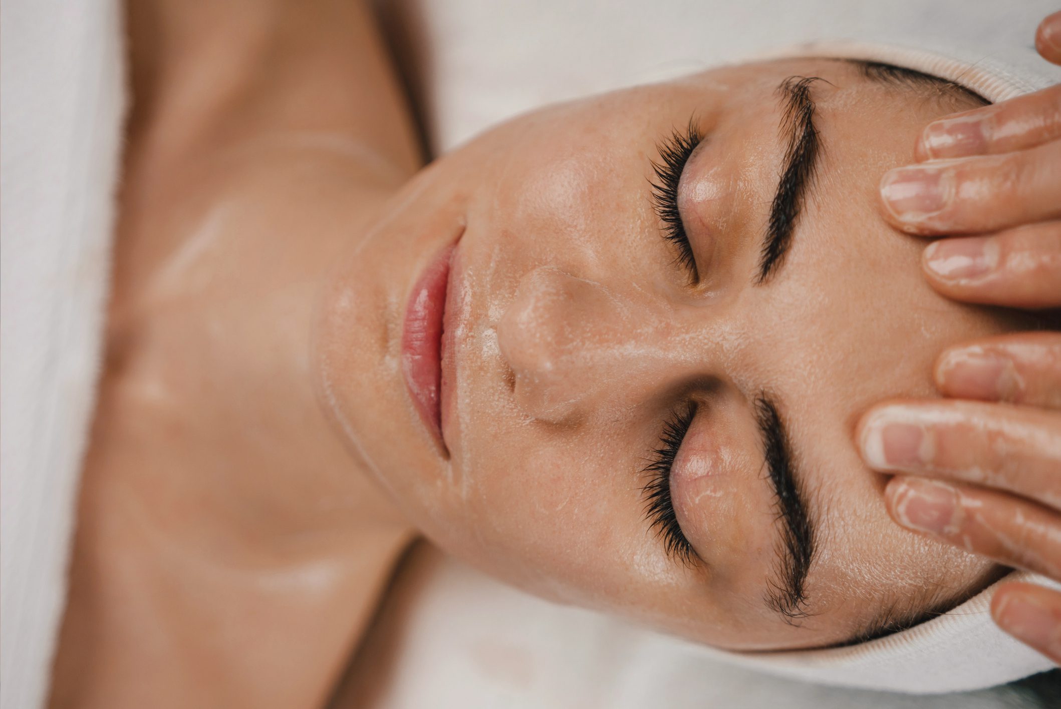 Shot of a beautiful young woman enjoying face massage at the beauty salon. Facial massage beauty treatment. Pinch and roll technique. A woman is getting her face washed with lotion.
