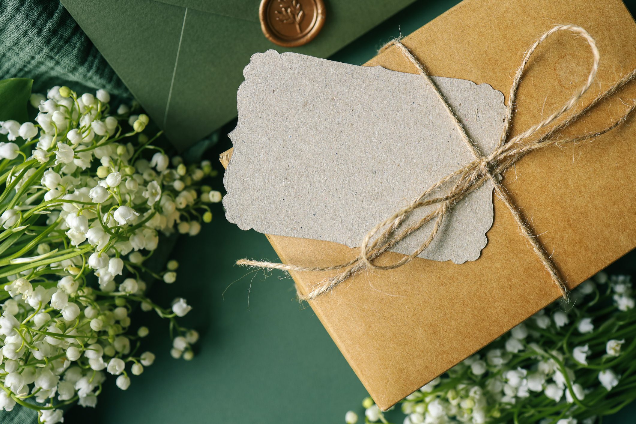 Craft gift box with space for text and a bouquet of lilies of the valley A brown envelope with a note on top of it.
